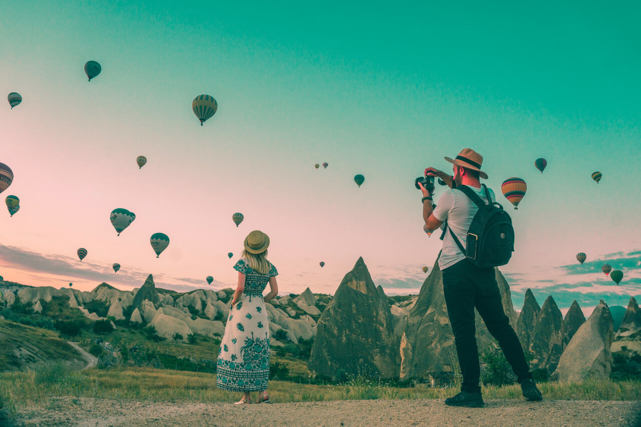 a man photographing lots of hot air balloons in the sky